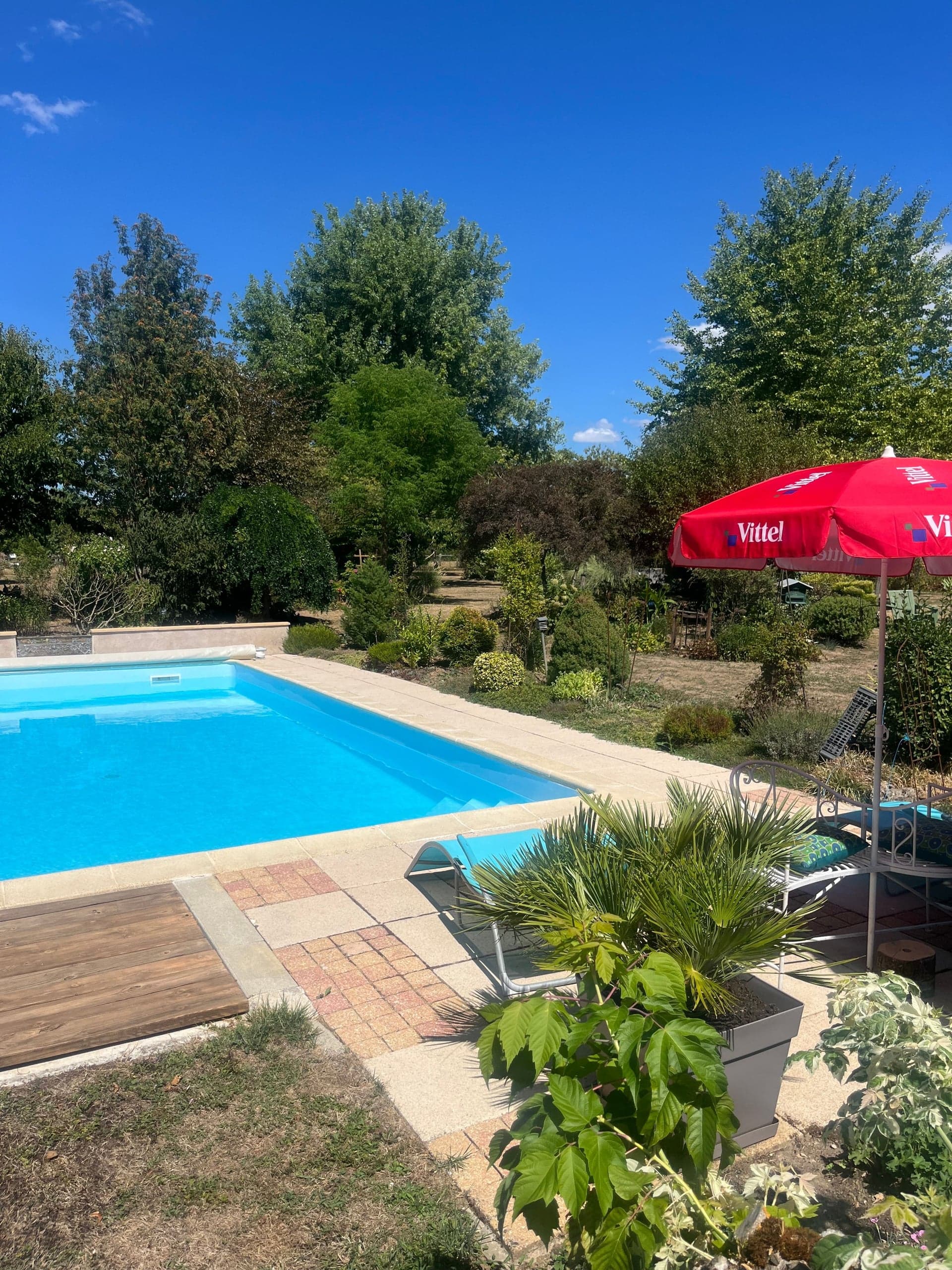 La piscine dans le jardin, plage en bois et parasol